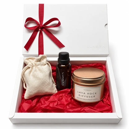 Set cadou de Crăciun Lunera cu Lava Rock Diffuser, recipient metalic cupru, ulei parfumat, săculeț din bumbac și cutie albă cu panglică roșie.